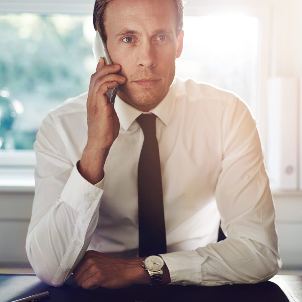 Portrait of business man talking on the phone with documents on the desk